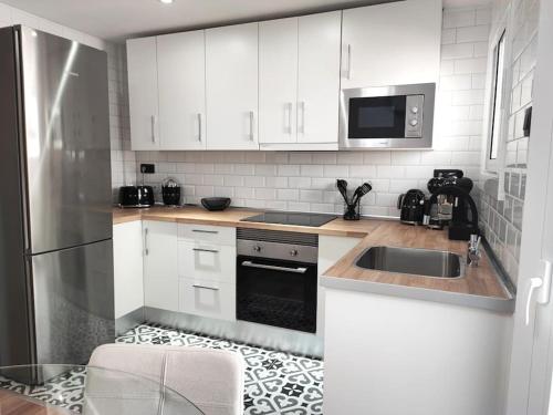 a kitchen with white cabinets and a stainless steel refrigerator at Cosy flat a few min to Barcelona emblematic sites in Cornellà de Llobregat