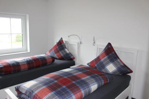 duas almofadas xadrez numa cama num quarto em Wohnung Zum Eisenlager em Norden