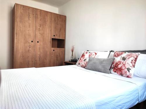 a bedroom with a white bed and a wooden cabinet at Cosy flat a few min to Barcelona emblematic sites in Cornellà de Llobregat