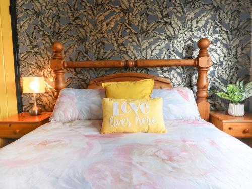 a bed with a wooden headboard with love was home pillows at The Yellow House in Withernsea