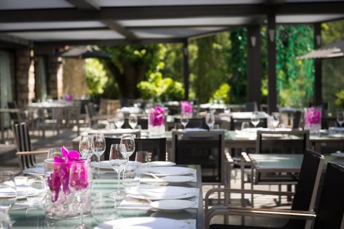 a table with white plates and glasses and pink flowers at Hostellerie Les Gorges De Pennafort in Callas
