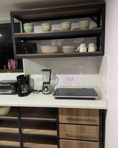 a kitchen with a counter top with a stove and dishes at Loft Mágico en Nativa Resort in Tarcoles