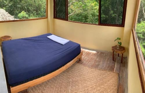 a bedroom with a bed in a room with windows at Rancho Aak in Yaxché