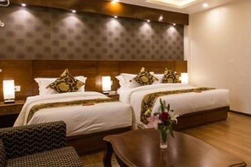 ein Hotelzimmer mit 2 Betten und einem Tisch in der Unterkunft Hotel Tulip in Jogīkuti