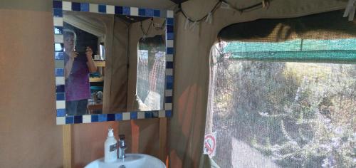 a person taking a picture of a mirror in a bathroom at Trees&Seas - Glamping with farm animals in Wilderness