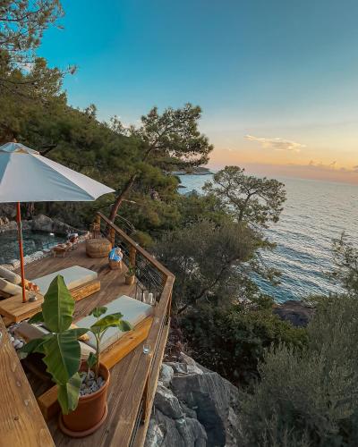 a deck with chairs and an umbrella and the ocean at Perdue Hotel in Faralya