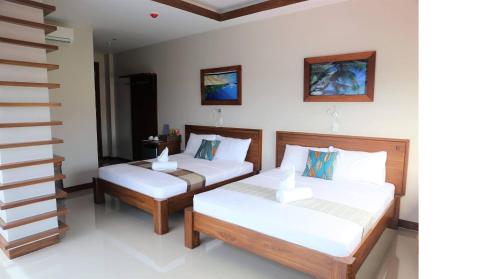 a bedroom with two beds and a staircase at Sunburn Suites and Rooftop Bar in Coron