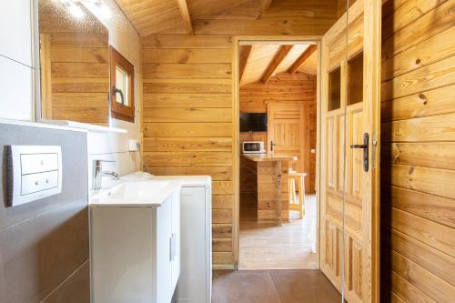 a bathroom with a white sink and a wooden wall at Mare E Monti Chalets in Porto Pollo