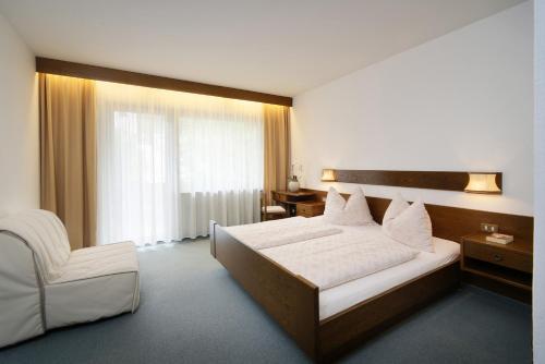 una camera d'albergo con letto e sedia di Egger Apartments a Rifiano