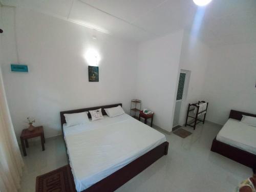 a bedroom with two beds in a white room at S & D Resort in Anuradhapura