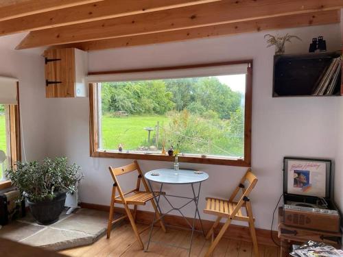 a room with a table and chairs and a window at The Cabin at Shambala- now with sauna available to book! in Whitby