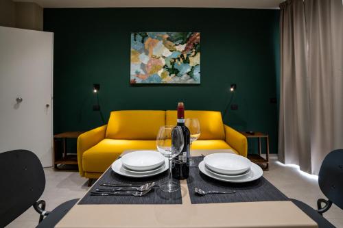 a dining table with a bottle of wine and a yellow couch at Virdamuri - Etna Country Resort in Giarre