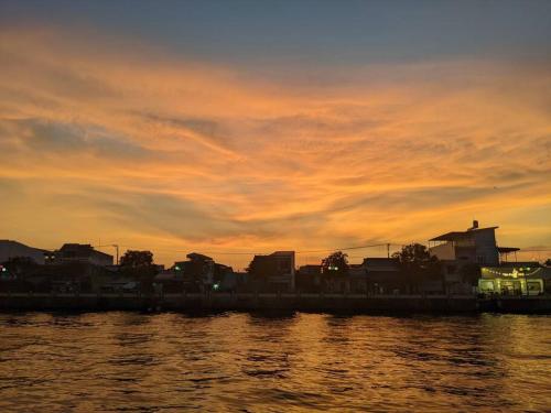 a sunset over a city with a body of water at Here Library - A wooden home by the river with a library in Thốt Nốt