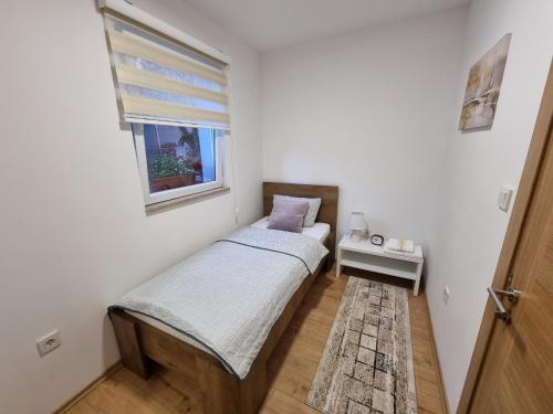 een kleine slaapkamer met een bed en een raam bij Lovely Apartment Sarajevo in Sarajevo