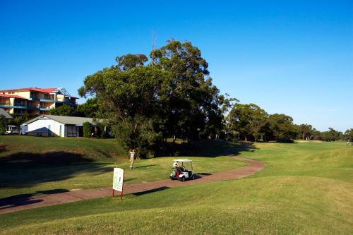 un carro de golf está estacionado en un campo de golf en Club Wyndham Port Stephens, en Salamander Bay