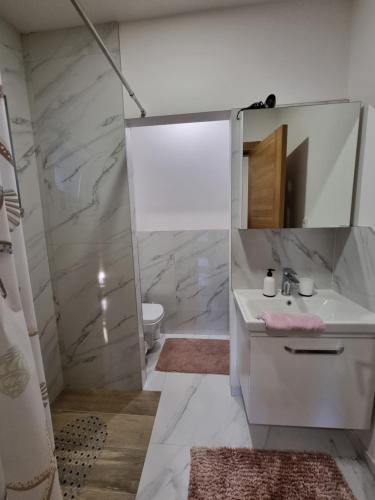 een witte badkamer met een wastafel en een spiegel bij Lovely Apartment Sarajevo in Sarajevo
