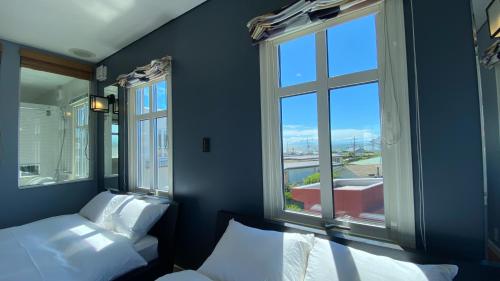 a bedroom with two beds and two windows at Tabinoteitaku Kamakura Yuigahama -Homann Concept- in Kamakura