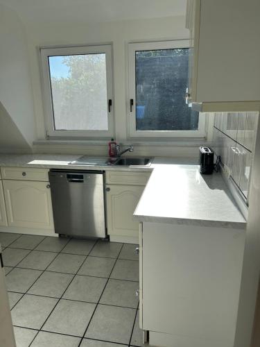 a white kitchen with a sink and two windows at FeWo Beim Museumsdorf in Buchholz in der Nordheide