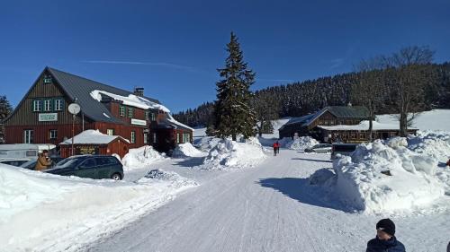 a street covered in snow next to a lodge at Útulný byt v Jizerských horách -Apartmán Mili in Kořenov