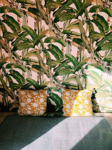 Cette chambre comprend 2 oreillers et un mur orné de plantes. dans l'établissement Logement pour 2 près de la seudre, à Nieulle-sur-Seudre