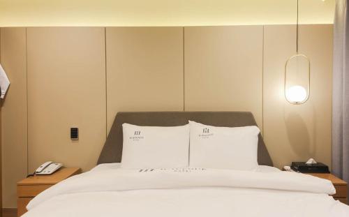 a bedroom with a bed with white sheets and pillows at H Avenue Hotel in Gyeongju in Gyeongju