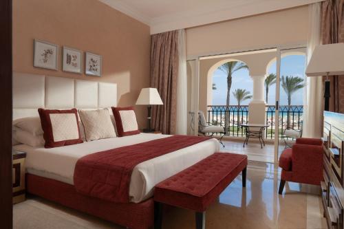 um quarto de hotel com uma cama grande e uma varanda em Jaz Almaza Beach Resort, Almaza Bay em Marsa Matruh