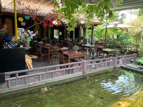 a koi pond in a restaurant with tables and chairs at Mandarin Homestay Hue in Hue