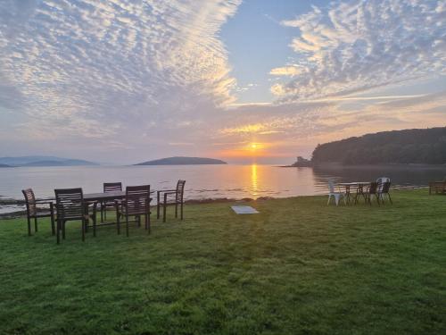a group of chairs and a table in front of the water at Balcary Bay Country House Hotel in Auchencairn