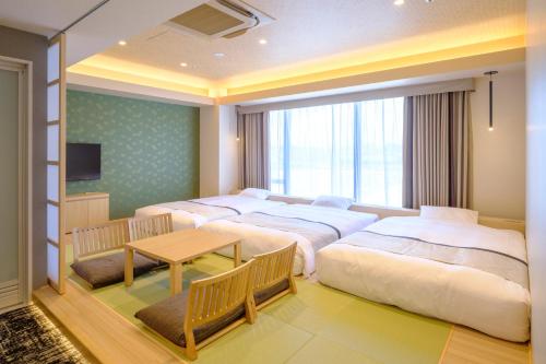 a hotel room with four beds and a table at Tosei Hotel Cocone Tsukiji Ginza Premier in Tokyo