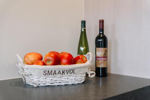 a basket of apples and a bottle of wine at BuitenGewoon Libeek in Sint Geertruid