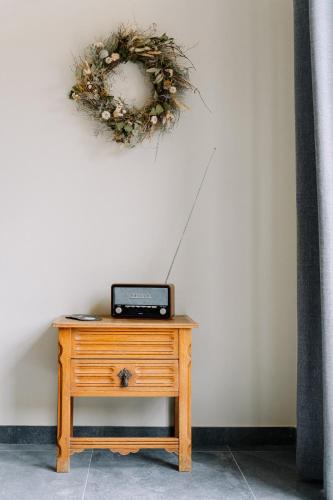 a table with a clock and a wreath on a wall at BuitenGewoon Libeek in Sint Geertruid