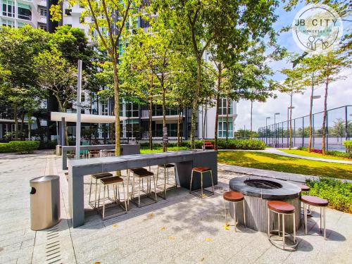 a table and stools in front of a building at Medini Signature Suites by RR JBcity in Nusajaya