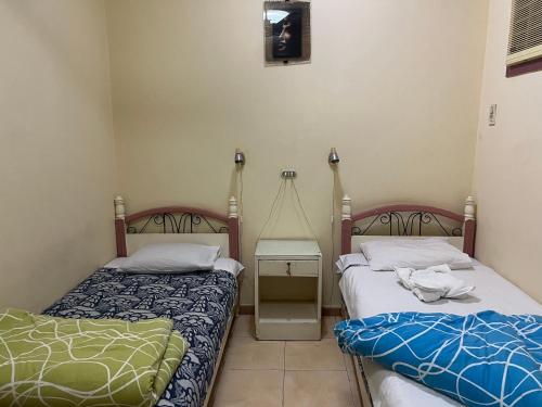 een slaapkamer met 2 bedden en een nachtkastje met bij Elphardous Hotel in Luxor
