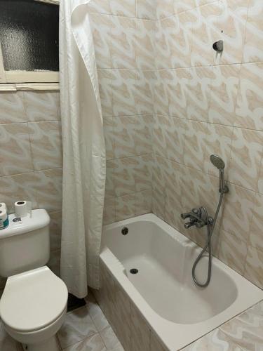 een badkamer met een wit toilet en een bad bij Elphardous Hotel in Luxor