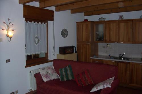 sala de estar con sofá rojo y cocina en Fabbricato Indipendente Centro, en Lozzo Cadore