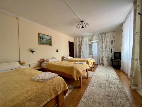 een hotelkamer met drie bedden en een televisie bij Guesthouse Alakol in Karakol