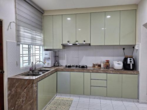 eine Küche mit grünen und weißen Schränken und einem Waschbecken in der Unterkunft SWEET PARADISE HOMESTAY in Parit Raja