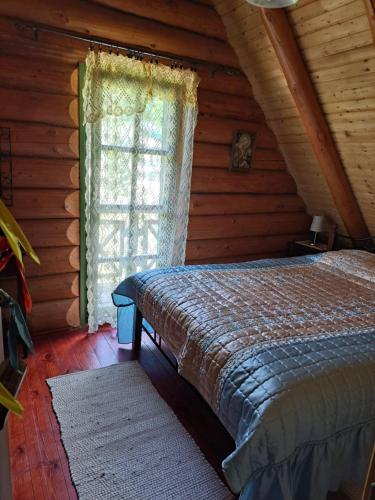 a bedroom with a bed and a window in a log cabin at Prigorka, a fairytale house in Jasenak