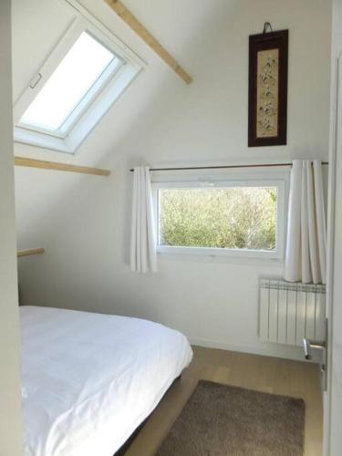 une chambre blanche avec un lit et une fenêtre dans l'établissement Villa calme et lumineuse à 500m de la plage, à Trévou-Tréguignec