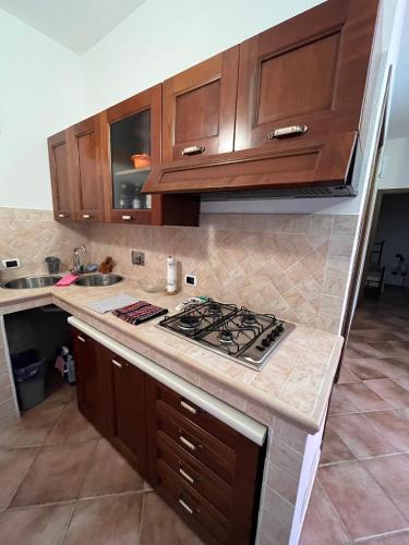 a kitchen with wooden cabinets and a stove top oven at Venti di Vacanza - Levante & Grecale in Olbia