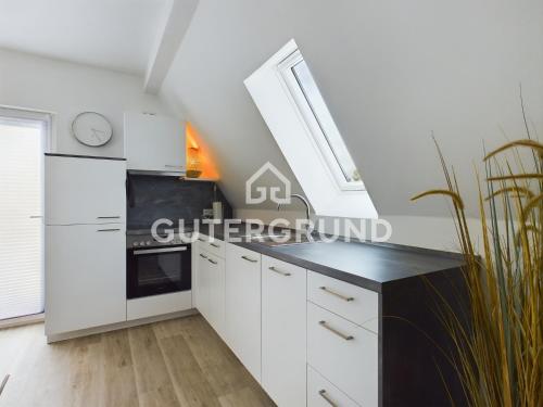 a kitchen with white cabinets and a clock on the wall at Studio-Apartment "Charlotte" in Westerstede