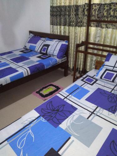 2 camas en una habitación de color púrpura y azul en Chathuni Holiday Home, en Anuradhapura