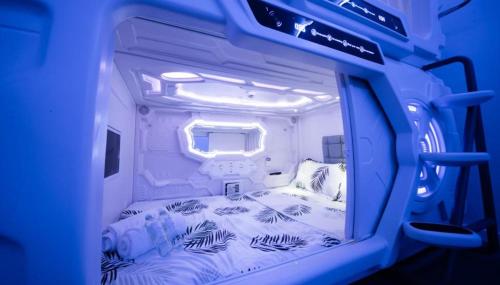 małą sypialnię z łóżkiem w niebieskim pokoju w obiekcie GOOD VIBES ONLY Capsule Hostel Malaga w Maladze