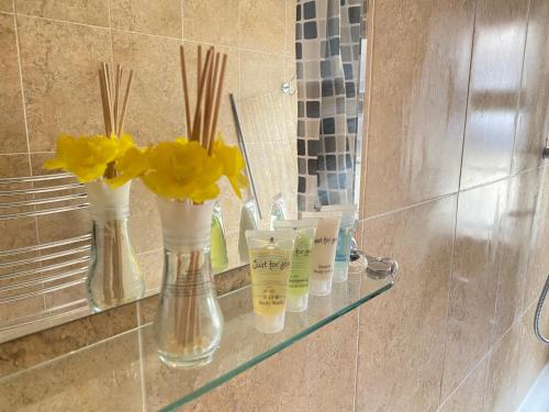a bathroom counter with vases with yellow flowers on it at Stunning 1-Bed Apartment in London in London