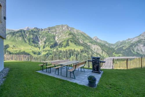 a picnic table with a grill and mountains in the background at HUS23 with Wellness in Schröcken
