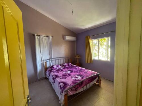 a bedroom with a bed with purple sheets and a window at Cozy duplex for perfect getaway in Grand Gaube