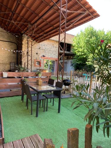 a patio with a table and chairs on green grass at Adorable Guest House « bienvenue chez vous ! » in Bordères-sur-lʼÉchez
