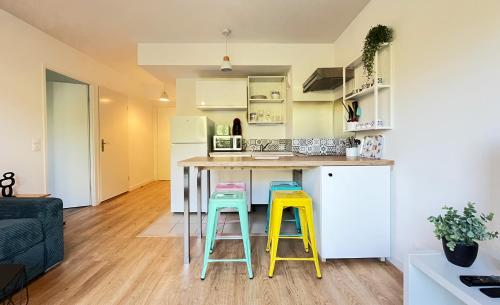 a kitchen with yellow and blue stools at a counter at Le 24 Nautic, Appartement douillet Bassin olympique Disneyland & Paris avec parking in Vaires-sur-Marne