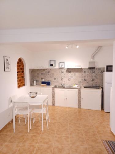 a kitchen with a white table and white chairs at Monte do Ti'Mota in São Lourenço de Mamporcão