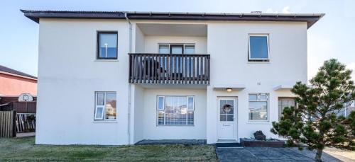 Cette maison blanche dispose d'un balcon. dans l'établissement Sól - S12 guesthouse, à Keflavík